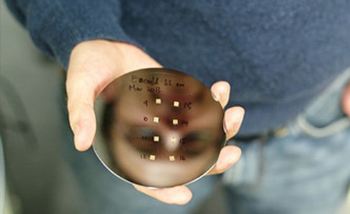 A polished silicon wafer held up to the light